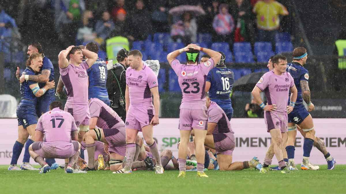 Scotland’s dejected players look on in disbelief as Italy celebrate a famous win in the Roman rain