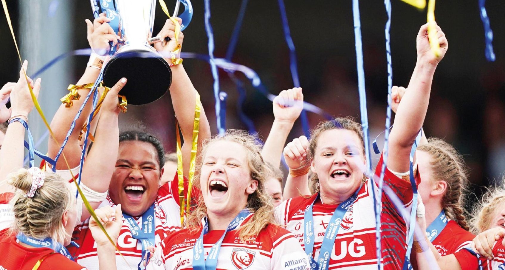 England stars Natasha Hunt and Zoe Aldcroft celebrate as Gloucester-Hartpury’s Sisilia Tuipulotu lifts the trophy last season
